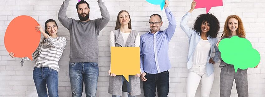Symbolising having cooperative conversations in order to increase workplace inclusivity and diversity, this photo is of men and women of all ages and colours holding different shaped speech bubbles